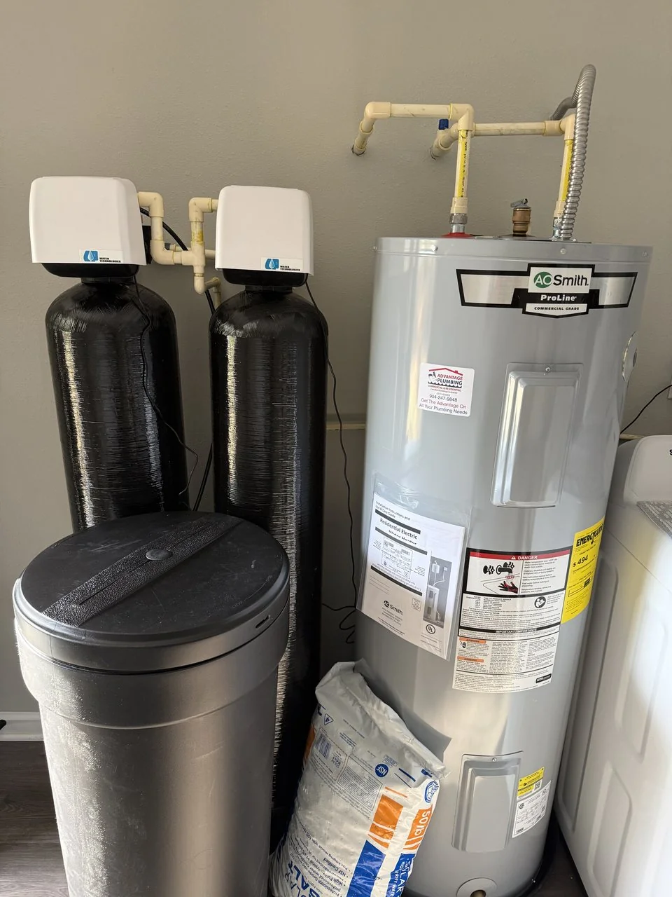 Water softener and filtration tanks installed alongside a water heater